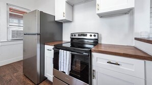 A modern kitchen with stainless steel appliances, white cabinetry, and a wooden countertop. - Coastal Sophistication (Galveston)