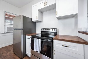 A modern kitchen with stainless steel appliances, white cabinetry, and a wooden countertop. - Coastal Sophistication (Galveston)