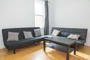 A modern living room with a grey sofa set, a coffee table, and a window with curtains.