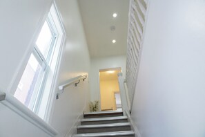 A staircase with white walls and a handrail, leading to a room with a door at the top. - Charming Stay in the heart of Chinatown. Explore and Have Fun (Ottawa)