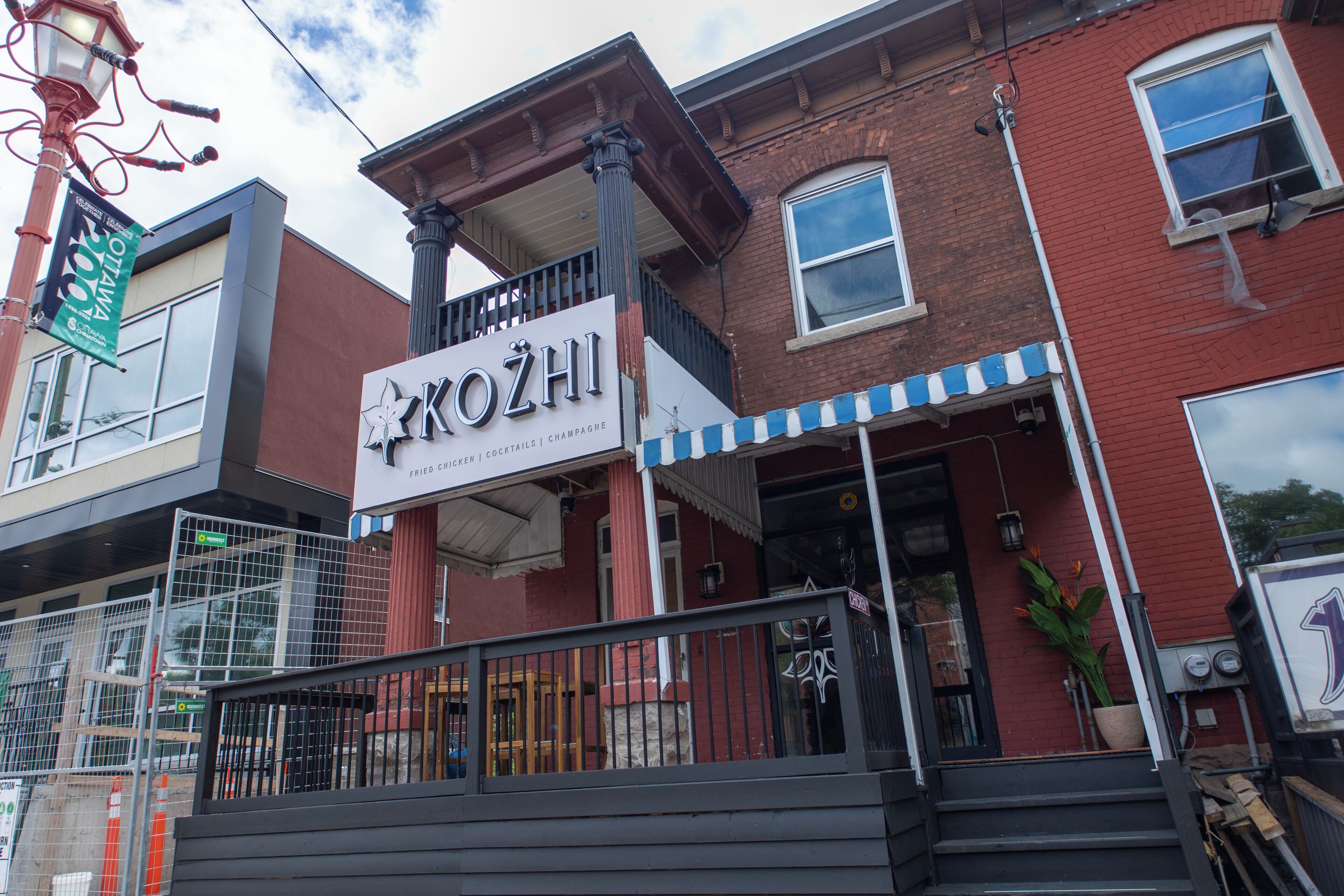 A building with a sign that reads 'KOZHI' and mentions 'Fried Chicken | Cocktails | Champagne'.