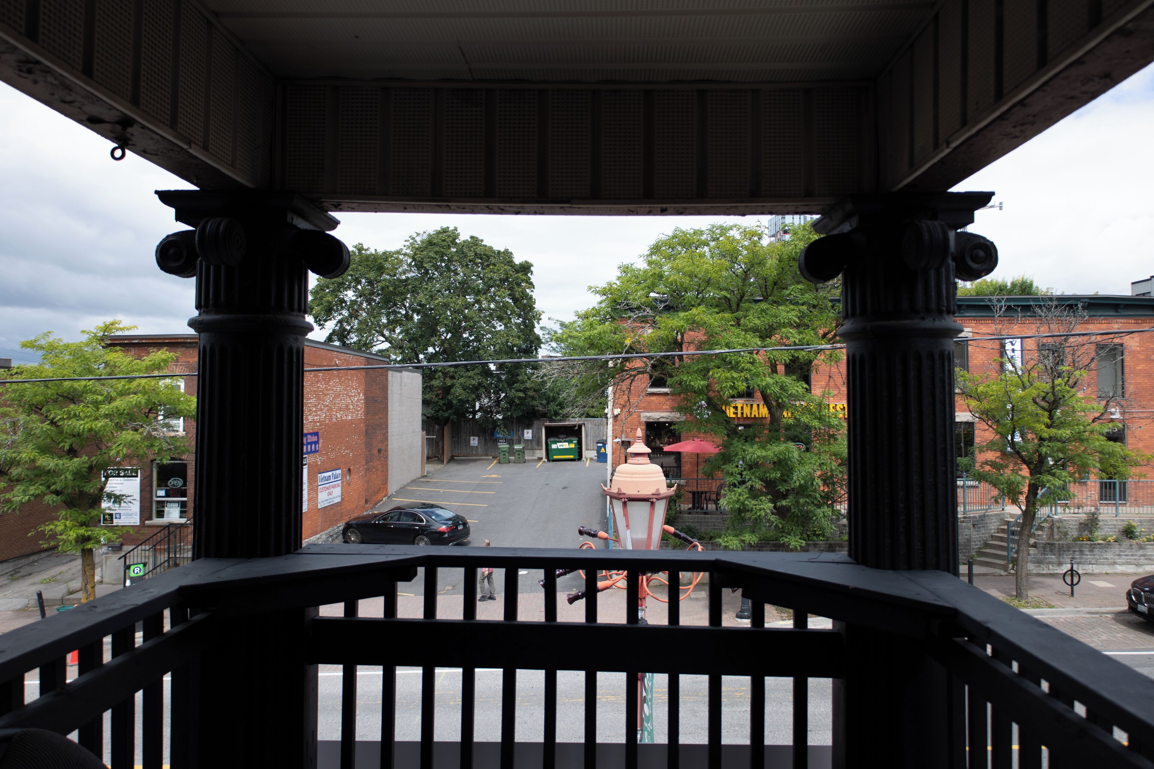 A covered outdoor area with a view of a street, including a building with a sign that reads 'Vietnam.'