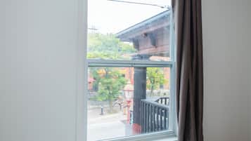 A window with a view of a building with columns and a tree outside.