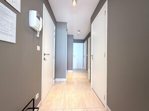 A hallway with grey walls, white doors, and a tiled floor. - Middelkerke Beach Apartment (Middelkerke)