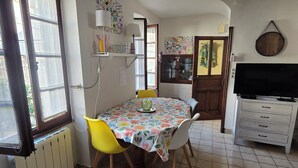 A dining area with a table, chairs, a radiator, and a TV. - Charming home in the heart of the Corbières region – Patio, courtyard. (Fabrezan)