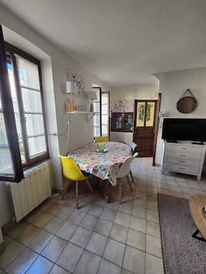 A dining area with a table, chairs, a radiator, and a TV. - Charming home in the heart of the Corbières region – Patio, courtyard. (Fabrezan)