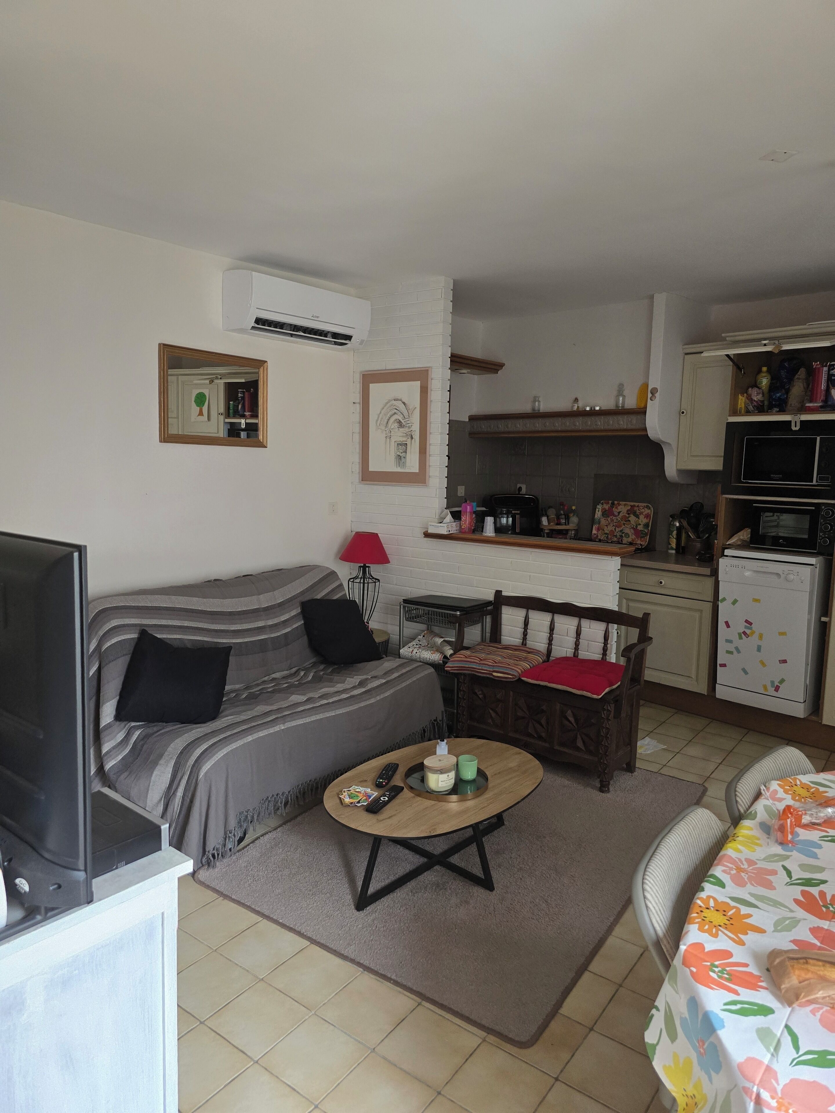 A compact living space with a sofa, a coffee table, a dining area, and a kitchenette.