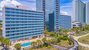 A hotel with multiple floors, a swimming pool, and a landscaped area with palm trees. - Oceanfront Serenity at Yachtsman S804 (Myrtle Beach)