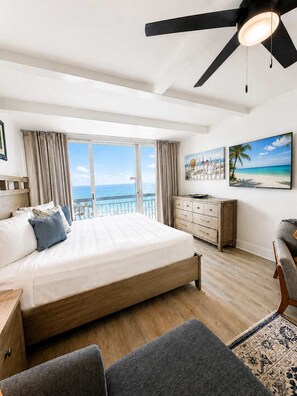 A bedroom with a large bed, a ceiling fan, a dresser, and a view of the ocean. - Oceanfront Serenity at Yachtsman S804 (Myrtle Beach)