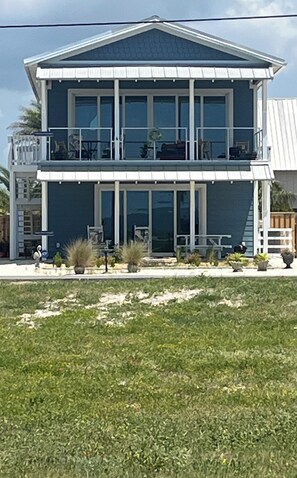 A two-story building with a balcony on the upper floor, large windows, and a flat roof. - Sweeping Gulf View 1 Block to the Beach - 1 Level Retreat in Mexico Beach! (Mexico Beach)