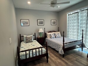 A bedroom with two wooden beds, a ceiling fan, and three framed pictures on the wall. - Sweeping Gulf View 1 Block to the Beach - 1 Level Retreat in Mexico Beach! (Mexico Beach)