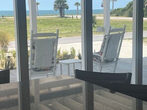 Blick von einem Zimmer mit Glastür und Balkon, der zwei weiße Stühle und einen kleinen Tisch bietet.
