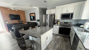 Uma cozinha moderna com bancadas de granito, eletrodomésticos de aço inoxidável e uma ilha central com banquetas.