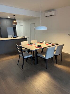 Ein stilvoller Essbereich mit einem Holztisch, grau gepolsterten Stühlen und einer Pendelleuchte.