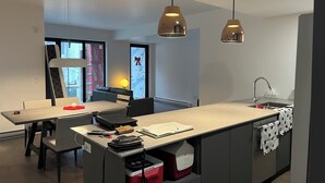 Uma cozinha moderna com uma ilha central, iluminação pendente e vista para o exterior.
