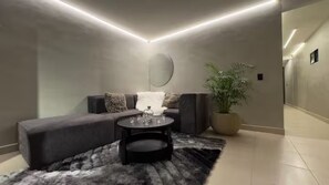 A modern living room with a sofa, a coffee table, and a potted plant. - Oasis Penthouse Poblado (Medellín)