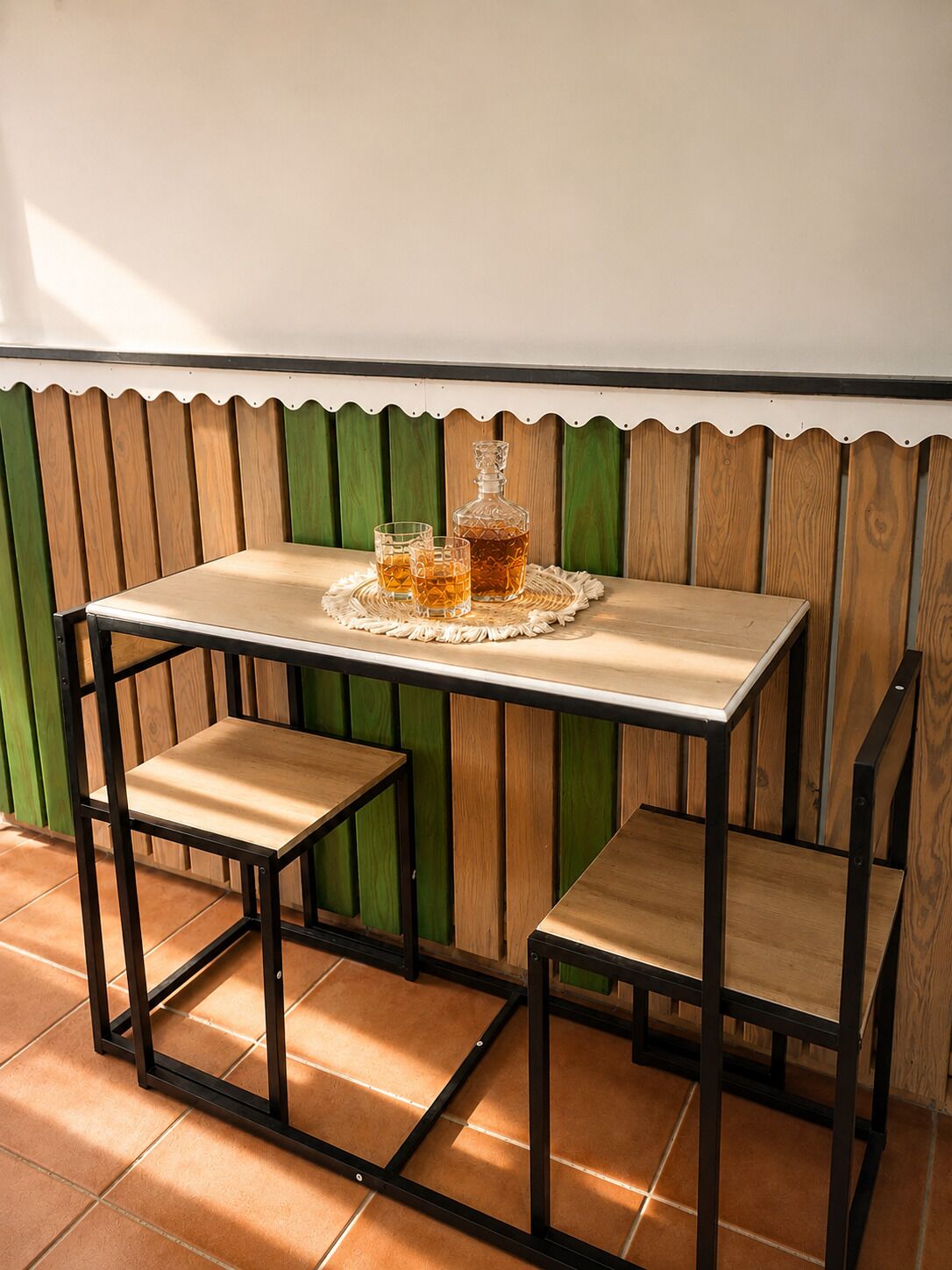 Une table avec une bouteille et des verres, placée devant un décor en bois avec un mur d’accent vert.