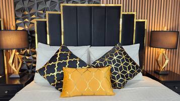 A bed with a geometric-patterned headboard, multiple pillows with geometric designs, and two bedside lamps.