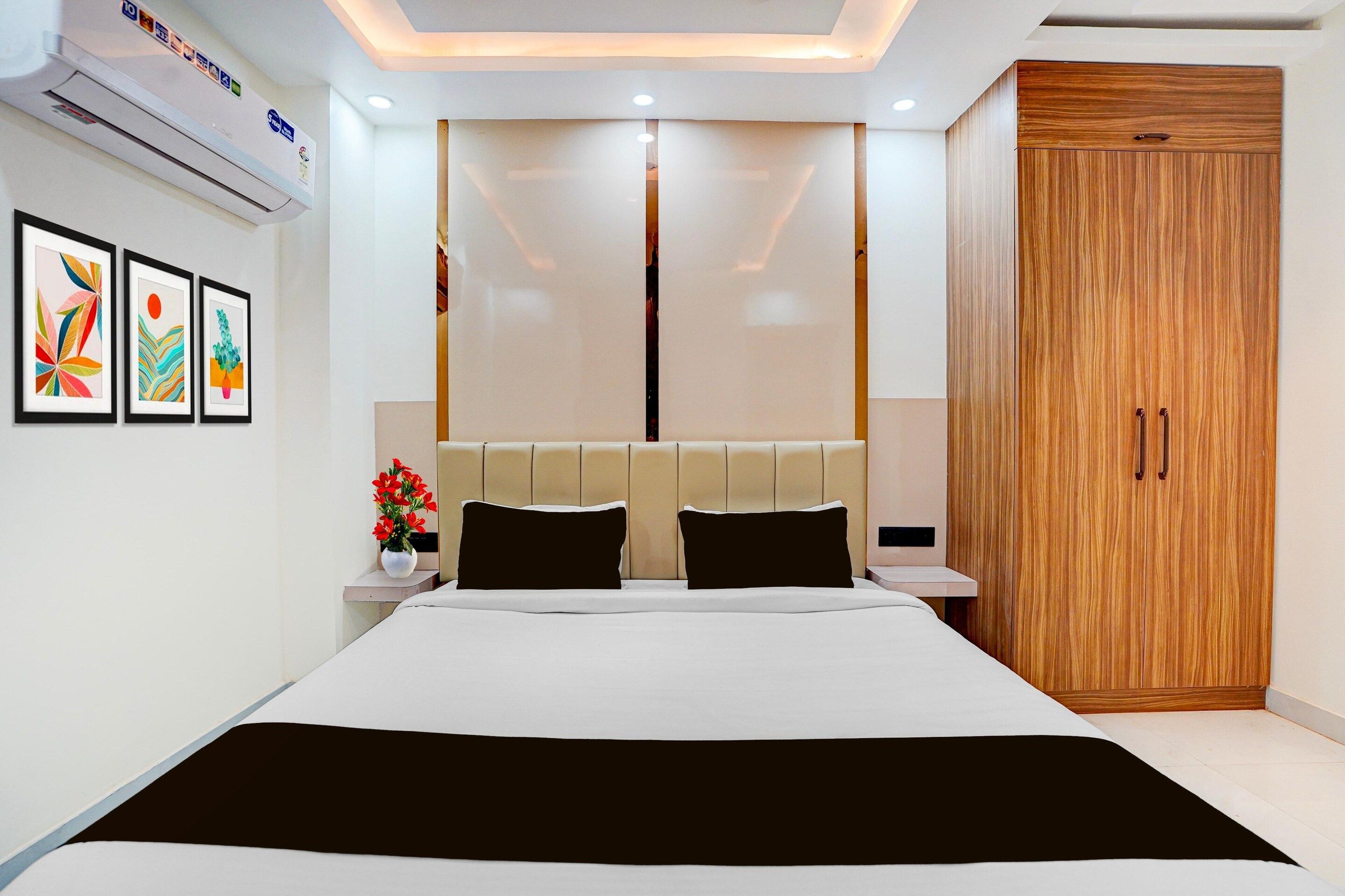 A modern hotel room with a large bed, a wooden wardrobe, and a wall-mounted air conditioner.