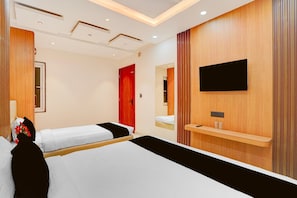 Ein Hotelzimmer mit zwei Betten, einer roten Tür, einem Wand-Fernseher und einer Wandverkleidung aus Holz.