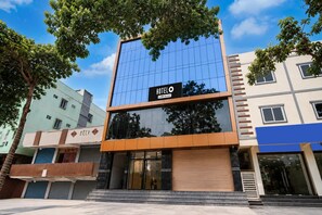 A modern hotel building with a glass facade, a sign reading 'HOTEL' and 'Yoyo-Serviced', and a staircase leading to the entrance. - Deluxe Hotel Genz Lavish Stays (Hyderabad)