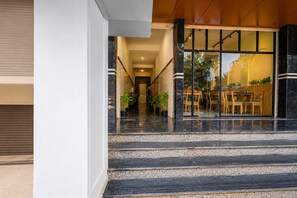Eine Hotelhalle mit einer Marmortreppe, die zu einem Essbereich mit Holzmöbeln und Blumentöpfen führt.