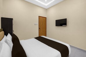 Ein Hotelzimmer mit einem Bett, einem Fernseher, einer Tür und einer Deckenleuchte.
