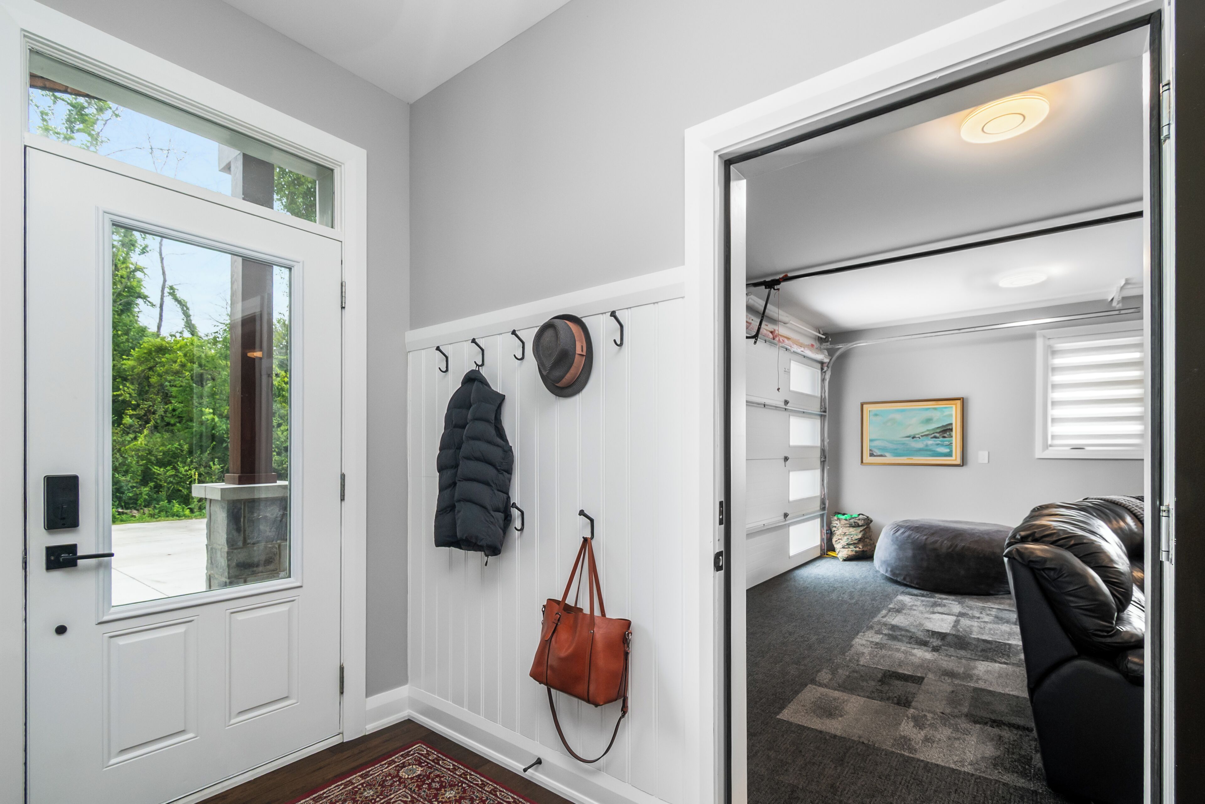 A hallway with a coat rack, a door leading to a garage, and a rug on the floor.