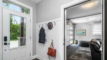 A hallway with a coat rack, a door leading to a garage, and a rug on the floor.