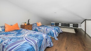 A bedroom with two beds, a dresser, a nightstand, and a built-in TV shelf.