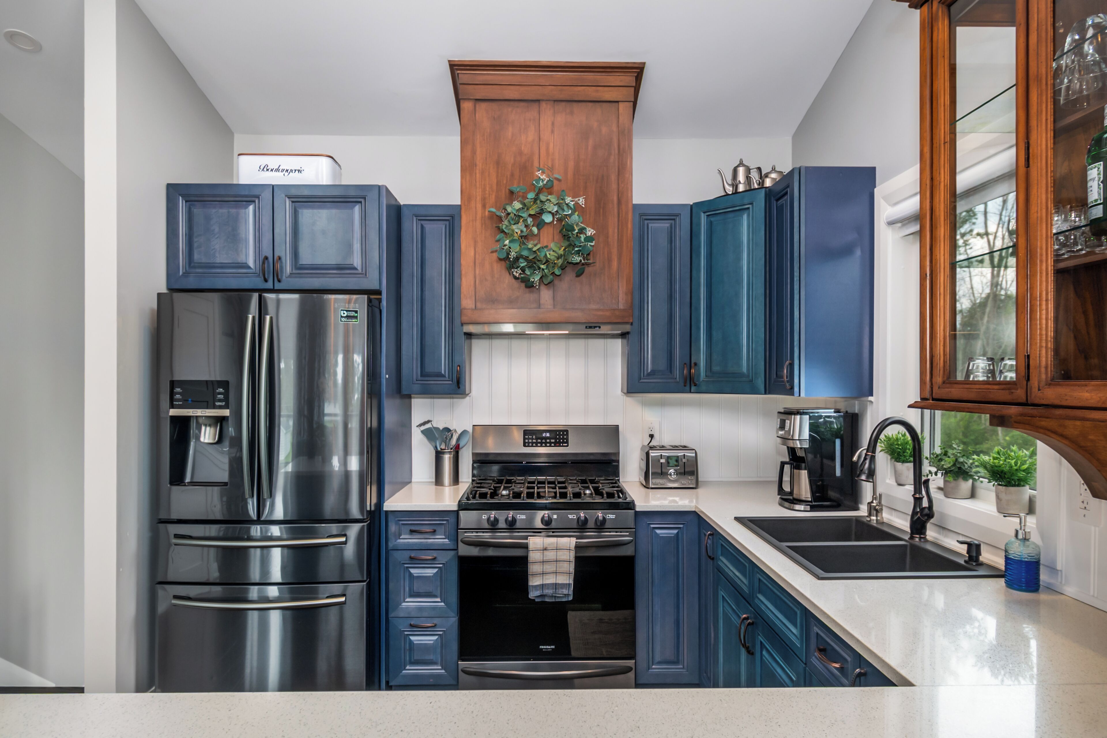Una cucina moderna con elettrodomestici in acciaio inossidabile, mobili blu e un festone decorativo.