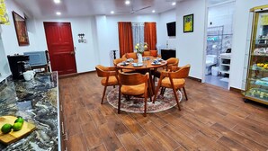 A dining area with a round table and chairs, a kitchen area with a red door, and a bathroom with a white toilet visible.