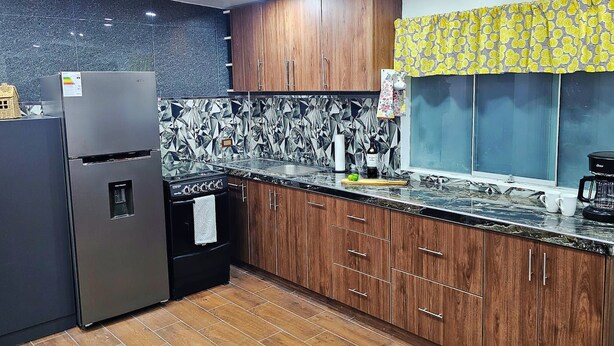 A modern kitchen with a refrigerator, stove, and wooden cabinets.