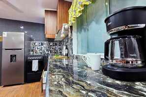 A modern kitchen with a marble countertop, stainless steel appliances, and a coffee maker.