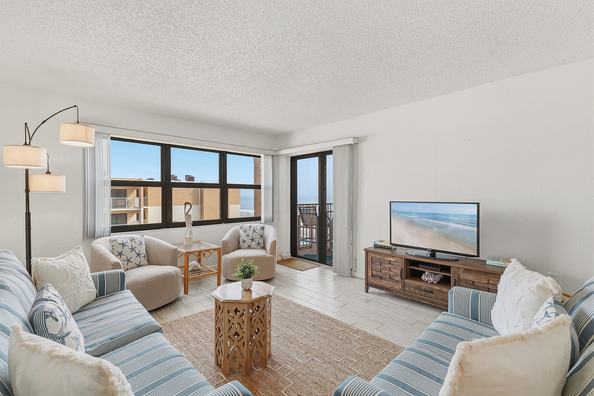 A spacious living room with a large window, a television, and a seating area with a sofa and armchairs.