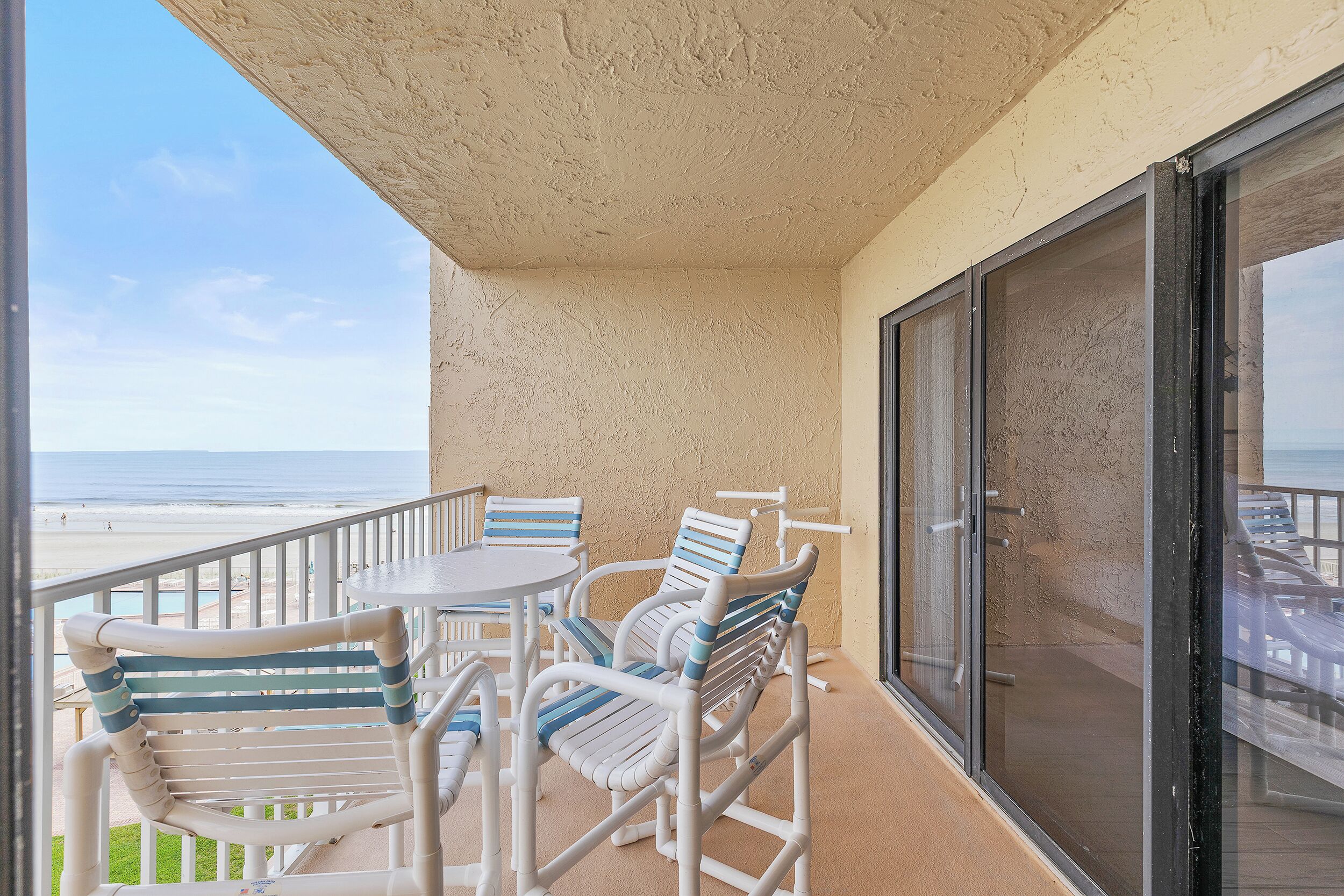 Un balcon avec vue sur la plage, équipé d’une table et de chaises.