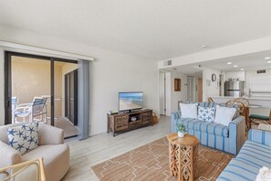A living room with a sofa, a television, and a dining area with chairs and a table. - 🌊Top Floor 1BR Condo | Ocean + Pool Views | Sleeps 4 | Castle Reef 527🌊 (New Smyrna Beach)