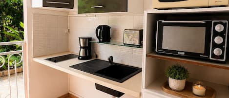 A compact kitchen with a built-in microwave, a coffee maker, and a toaster.