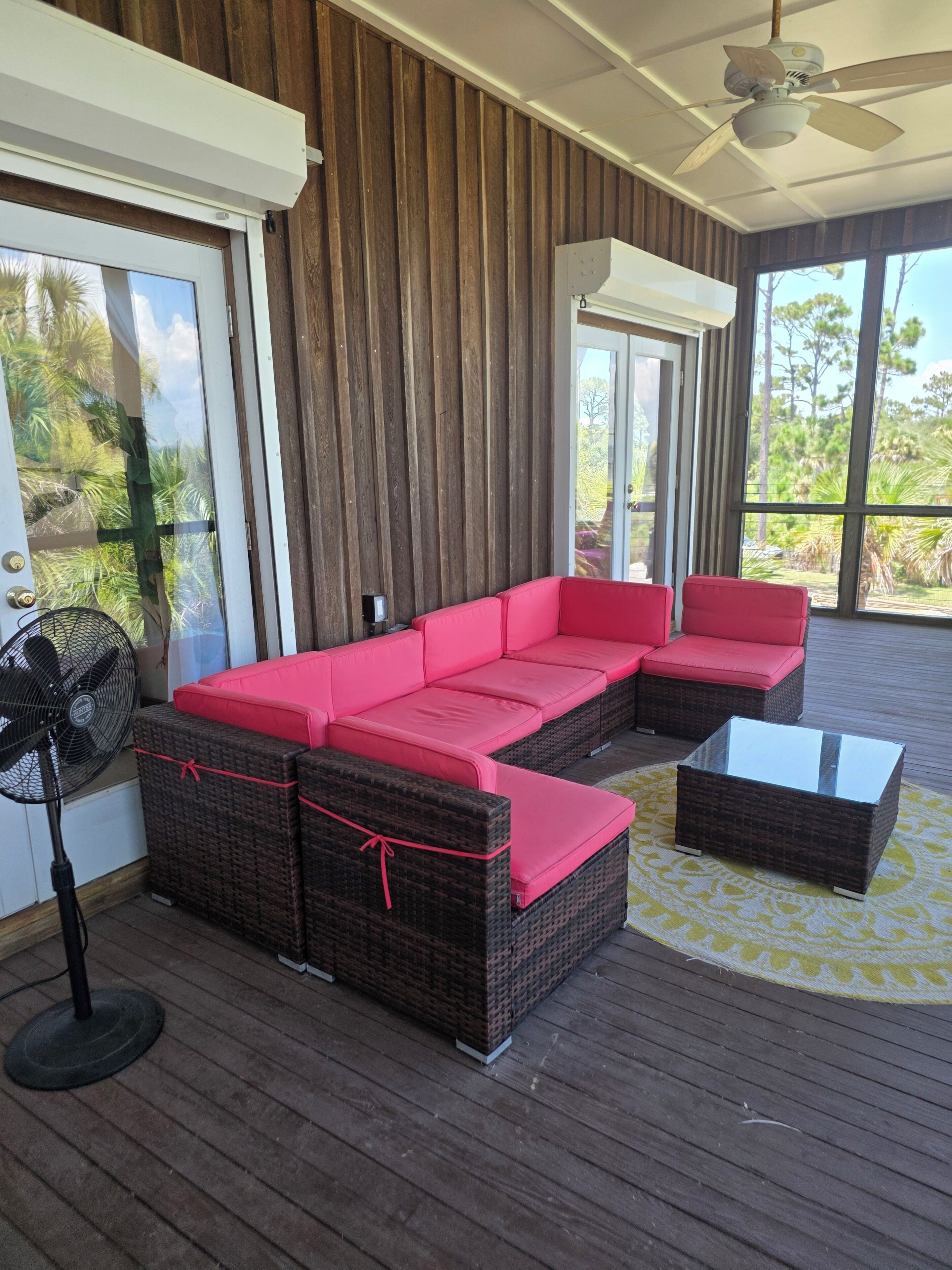 A covered outdoor seating area with wicker furniture and a ceiling fan.