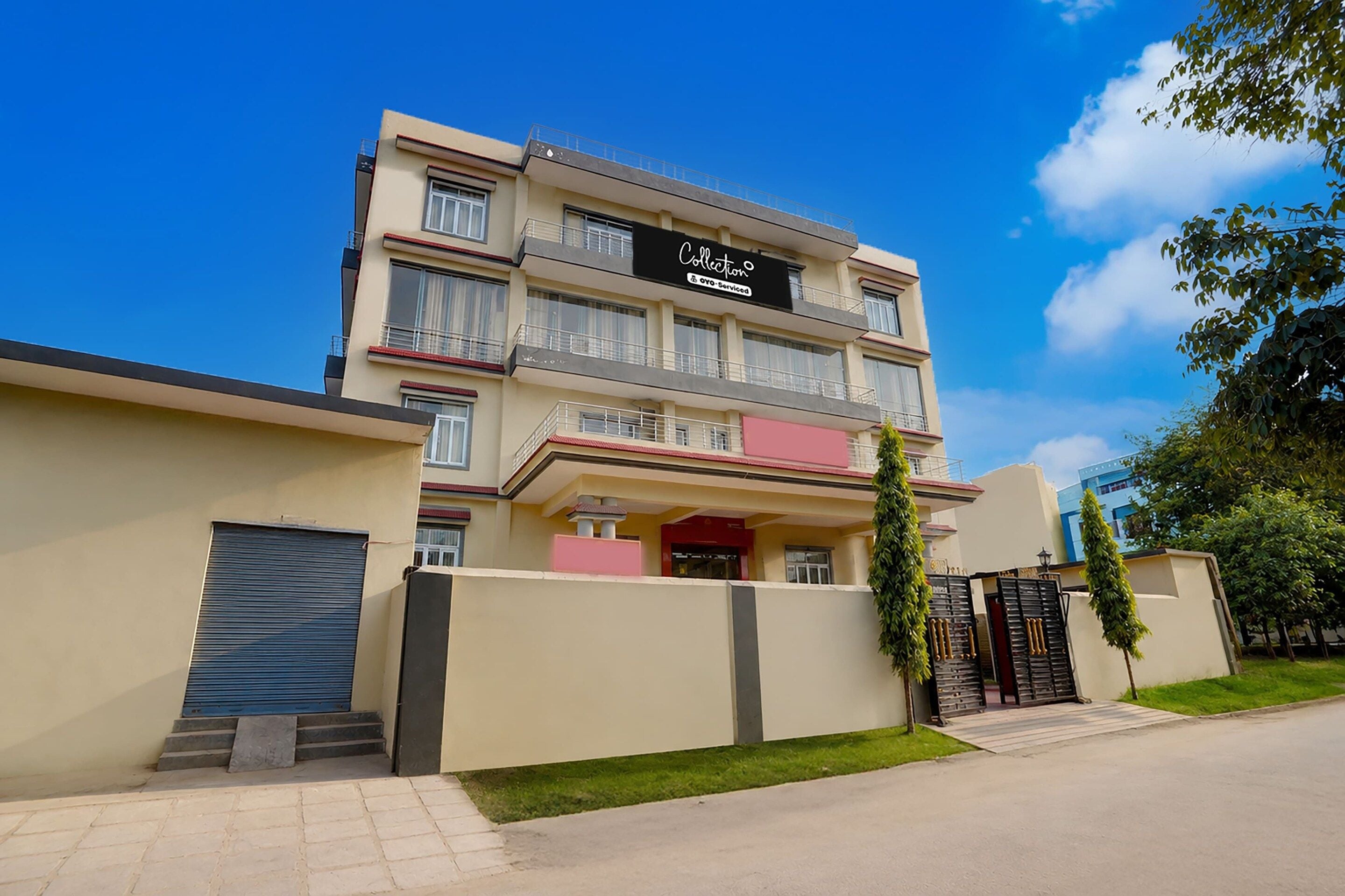 A multi-story residential building with a gated entrance, a visible balcony on the second floor, and a clear sky.