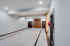 A spacious hallway with a marble floor, a fire extinguisher mounted on the wall, and a ceiling fan. - Collection O Dafi Crossway Varanasi (Varanasi)