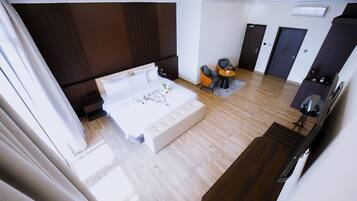 A modern hotel room with a large bed, a seating area with a small table, and a separate entrance door.