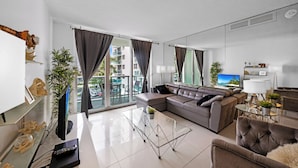 Una sala de estar moderna con un sofá modular, una mesa de centro de vidrio y un televisor de pantalla plana.