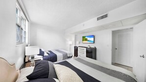 Habitación de hotel con dos camas, un televisor en la pared, un escritorio y una ventana.