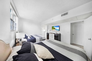 A hotel room with two beds, a TV on the wall, a desk, and a window. - Beautiful apartment in community with pool and beach in HOLLYWOOD BEACH MIAMI (Hollywood)
