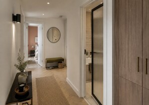 Un couloir avec un banc, un miroir et une porte donnant sur une salle de bain.