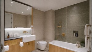 Un baño moderno con tocador doble lavabo, inodoro y bañera independiente.
