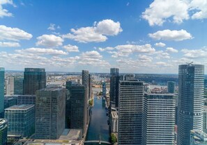 A cityscape with modern high-rise buildings, a river, and a clear sky. - The Thames Horizon Luxury Skyline in Canary Wharf (London)