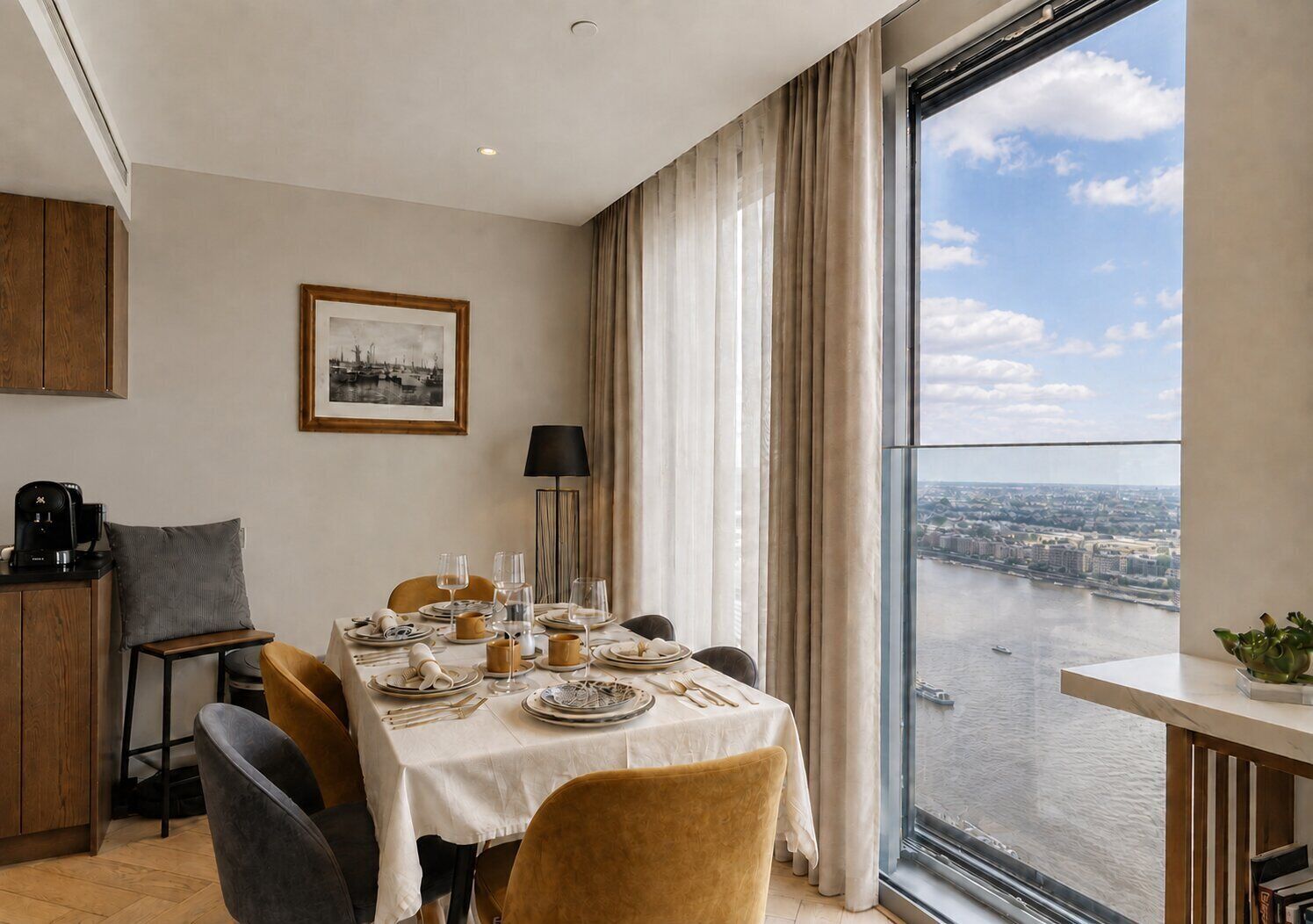 A dining area with a table set for four, a coffee machine, and a view of a river through large windows.