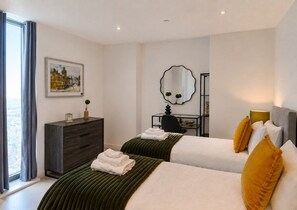 A hotel room with two beds, a desk, a mirror, and a painting on the wall. - The Thames Horizon Luxury Skyline in Canary Wharf (London)